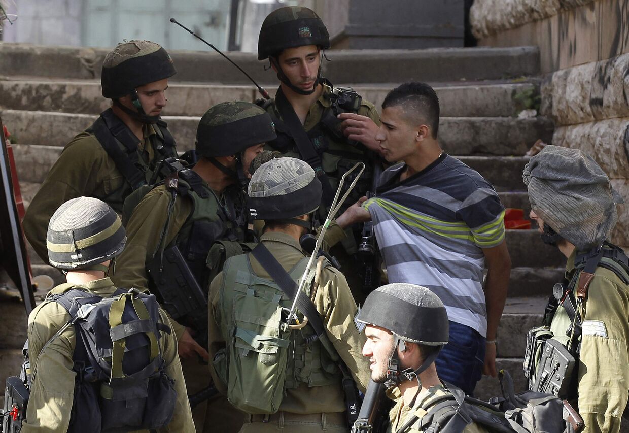 Израильские солдаты допрашивают палестинского юношу
