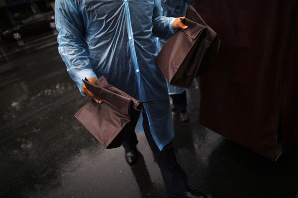 Работник Шанхайской похоронной службы несет сумки с прахом усопших