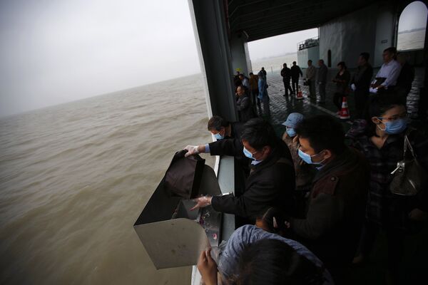 Человек бросает прах своих родственников в океан во время церемонии морских похорон в Шанхае