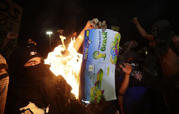 Протестующие сжигают рекламный буклет Чемпионата мира во время акции протеста в Рио-де-Жанейро
