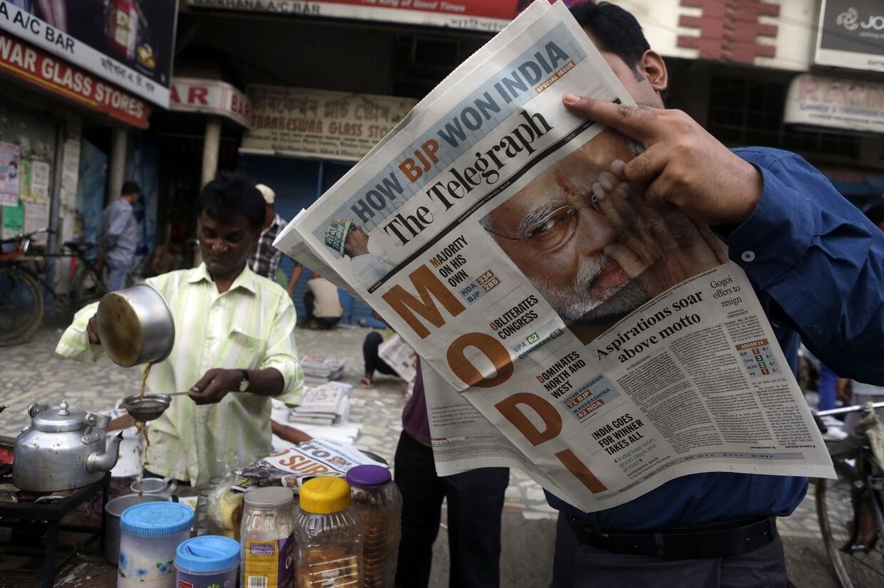 Мужчина читает газету с изображением Нарендры Моди 