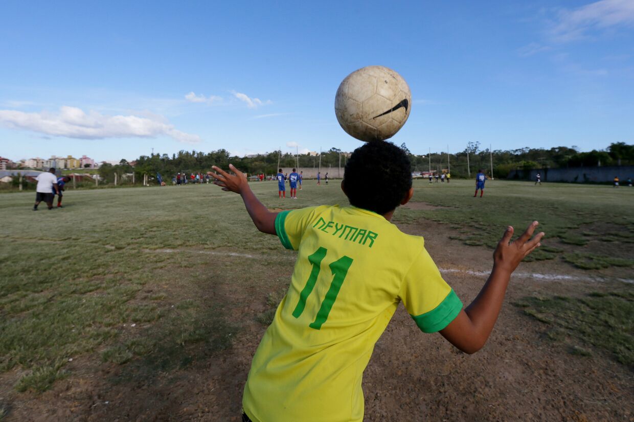 Мальчик в футболке с именем нападающего сборной Бразилии Неймара наблюдает за матчем-пеладой в окрестностях Порту-Алегри