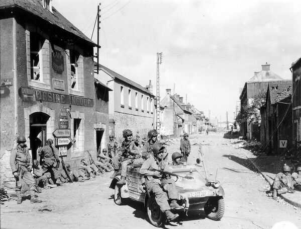 Американские солдаты едут на «Кюбельвагене» по городу Карантан