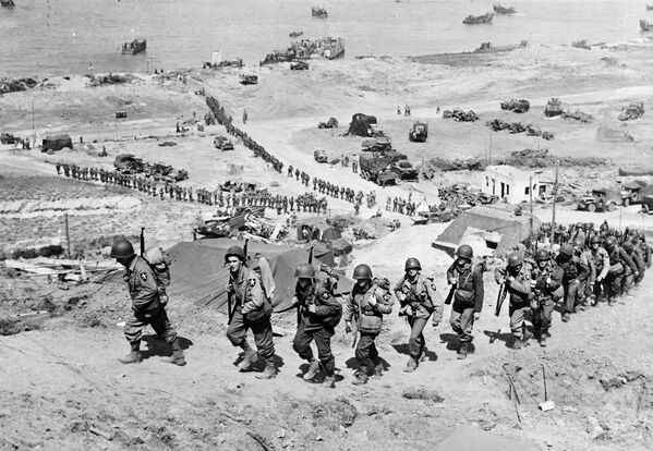 Американские солдаты поднимаются к немецкому бункеру после высадки на пляже Омаха
