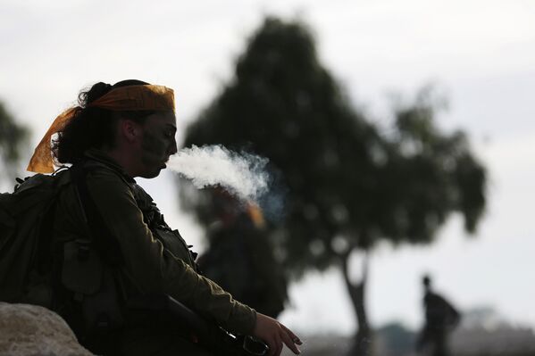 Девушка, служащая в батальоне Каракаль, курит после 20-тикилометрового маршрута по пустыне Негев