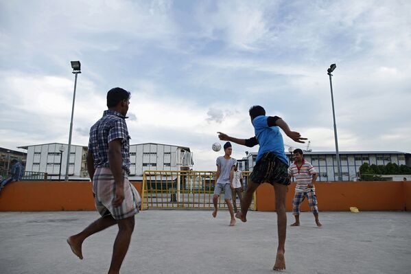 Мигранты из Индии и Бангладеша играют в футбол на улице Сингапура