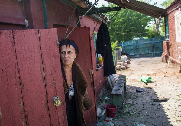 Женщина выглядывает из убежища после массированного артиллерийского обстрела поселка Черевковка под Славянском