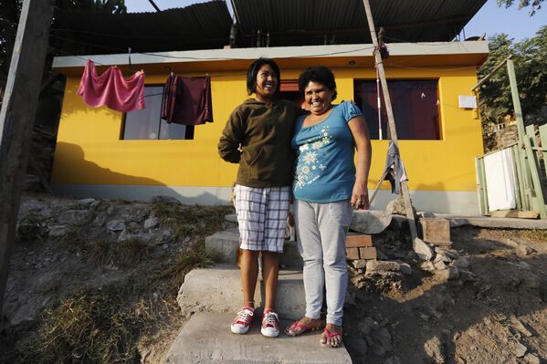 Грасьела Гузман с дочербю Марией у своего дома в трущобах Госен на окраине Лимы