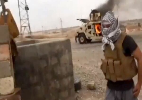 Боевик «Исламского государства Ирака и Леванта» у горящего «Хаммера» иракской армии 