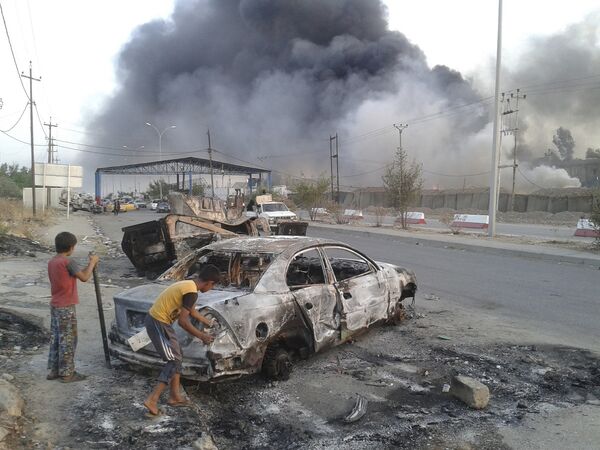 Дети у сгоревшей машины во время столкновений между иракскими войсками и организацией «Исламское государство Ирака и Леванта» городе Мосул
