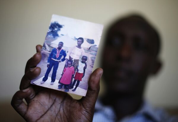 Патрик Маньика, переехавший в Калифорнию из Руанды, показывает фотографию своей семьи