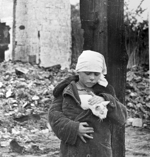 Девочка с котенком возле разрушенного дома