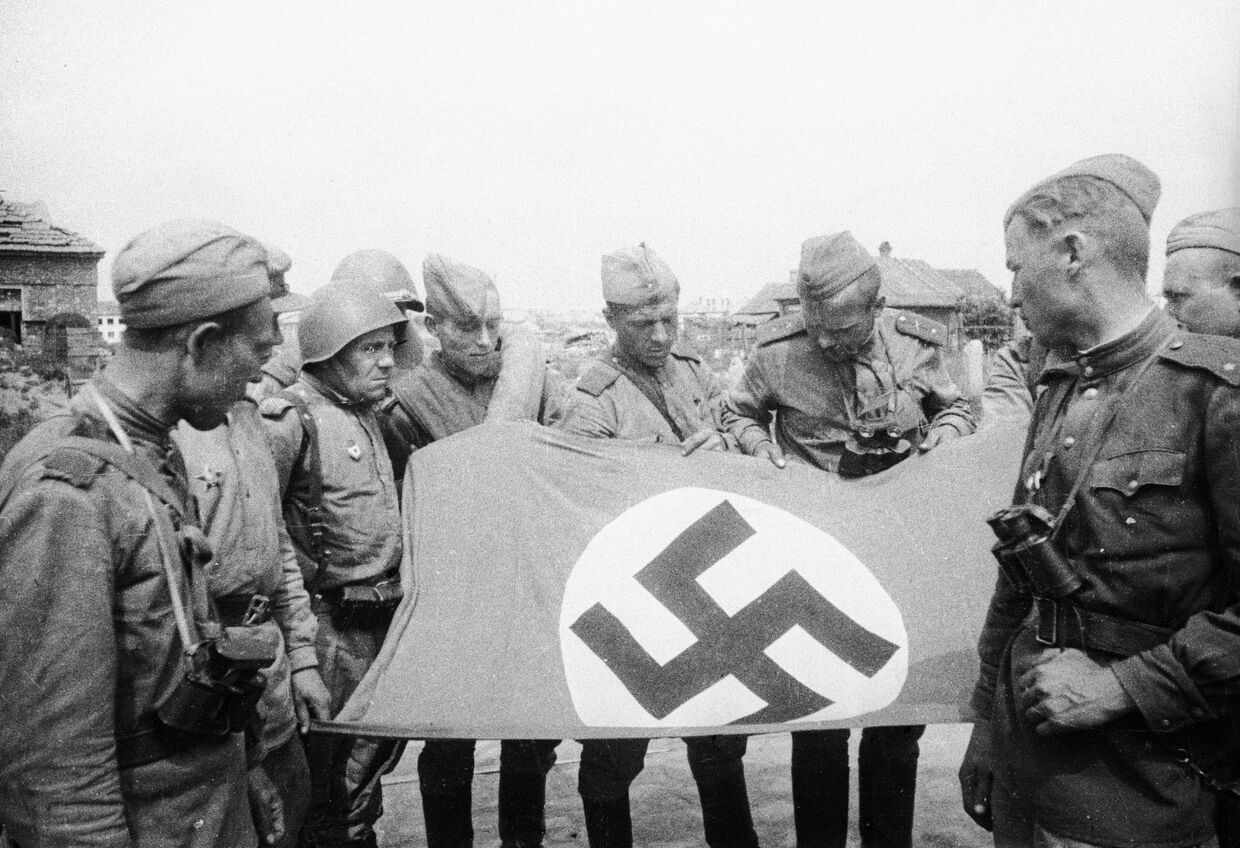 Советские воины рассматривают захваченное знамя одной из частей гитлеровцев. Витебск, 26 июня 1944 года