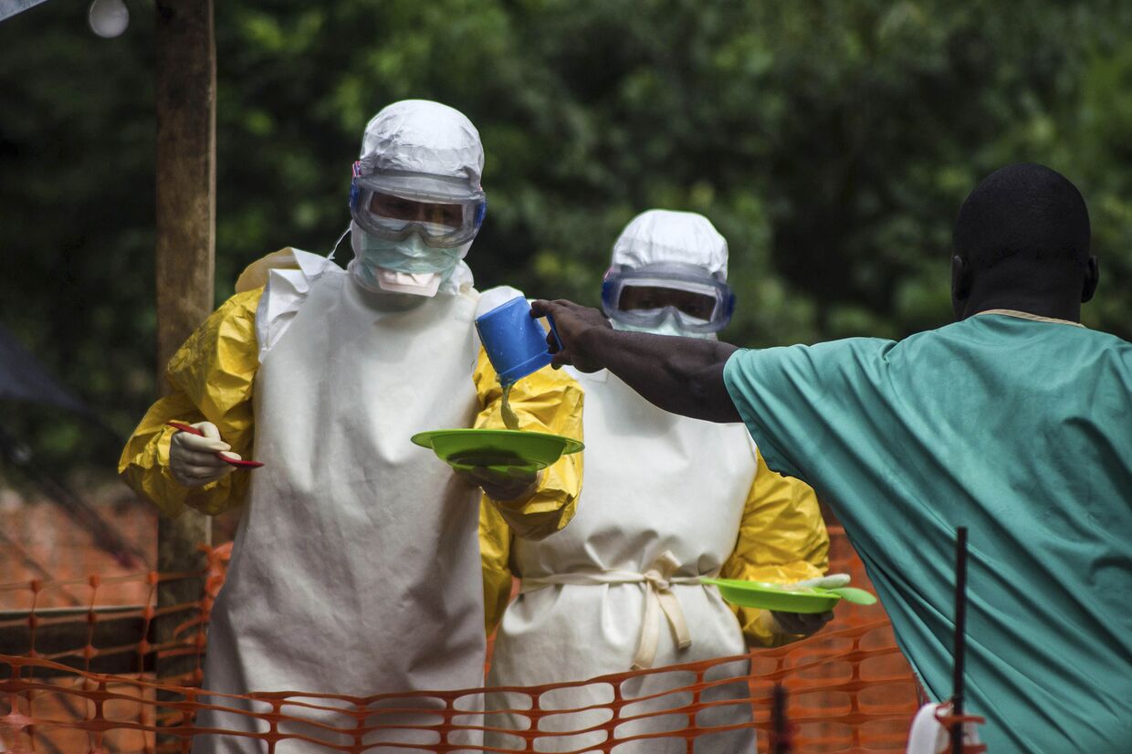 Медицинские работники, сотрудничающие с организацией «Доктора без границ», раздают еду пациентам Центра по лечению вируса Эбола в Кайлахуне