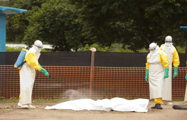 Медицински работники из организации Samaritan's Purse опрыскивают дезинфектантом тело умершего от вируса Эбола