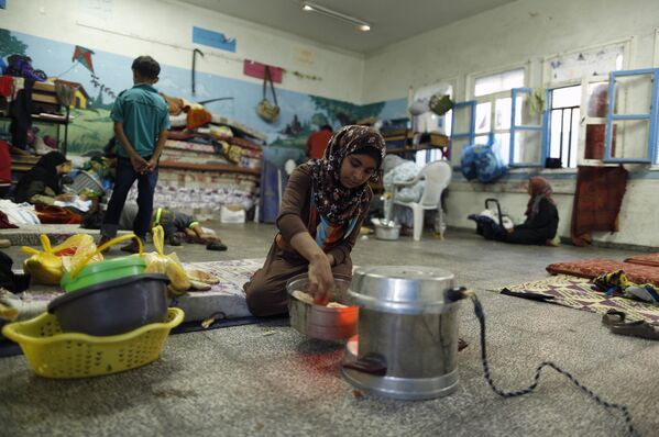 Палестинская девочка готовит еду в школе ООН в Газе