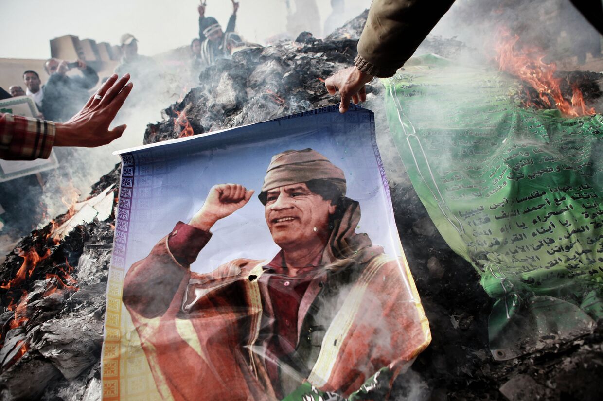 Житель Бенгази сжигает портрет Муамара Каддафи