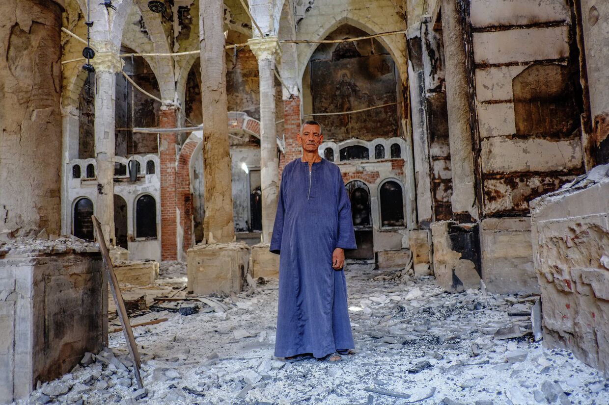 Копт в одной из сожженных и разрушенных коптских церквей в провинции Минья