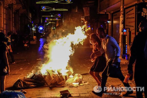 Прохожие идут мимо подожжённого мусора на улицах Стамбула