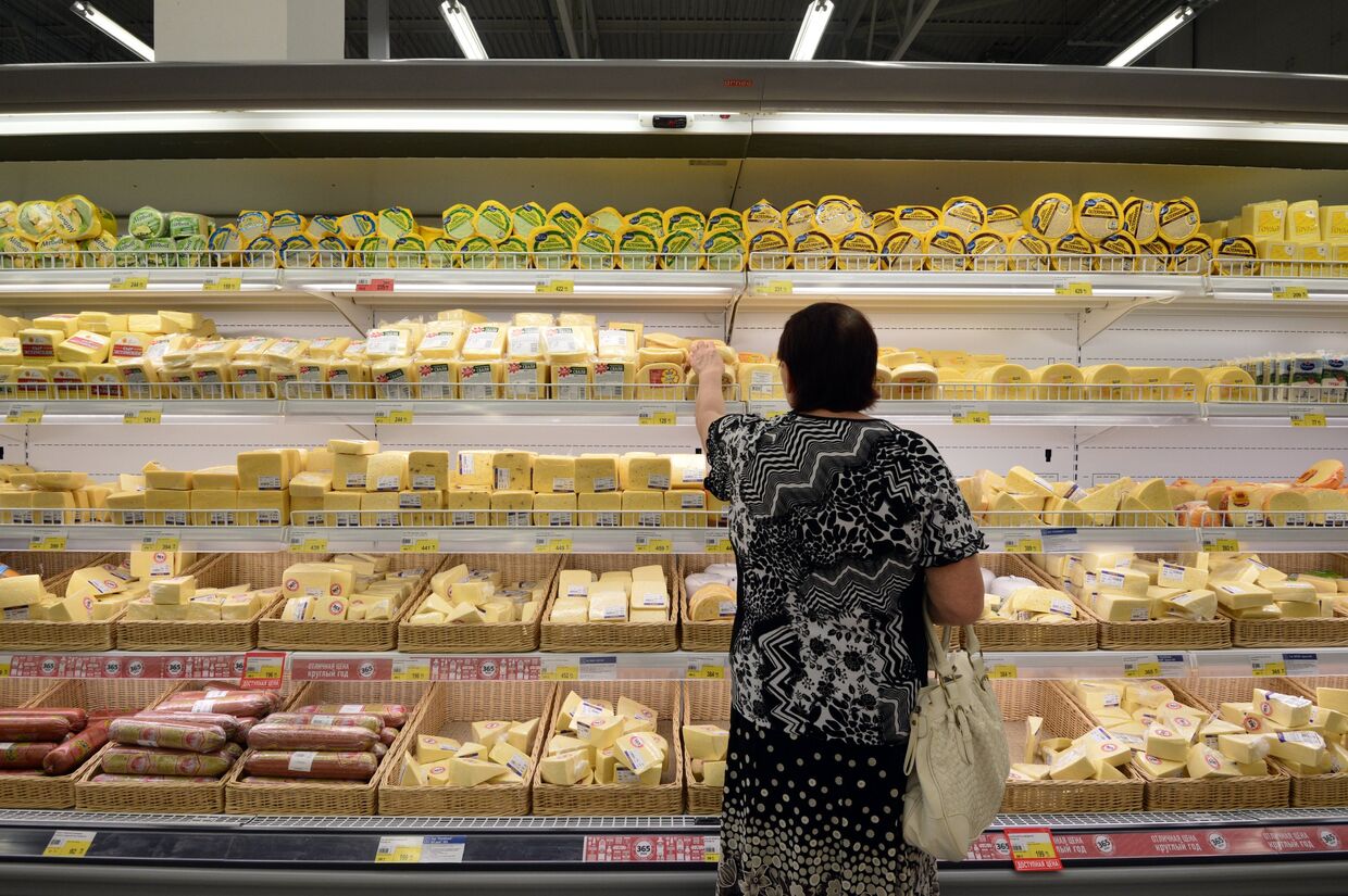 Женщина у прилавка с сырами в гипермаркете