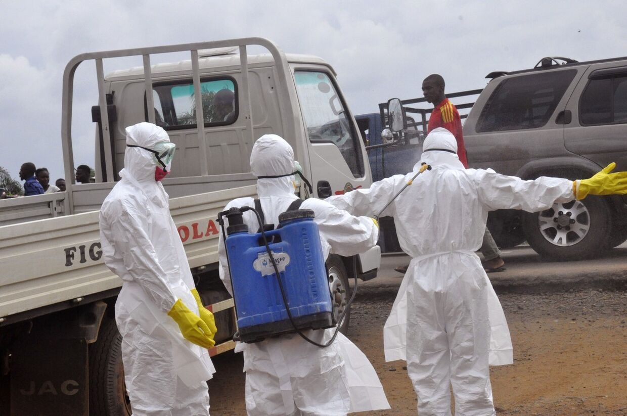 Медицинские работники опрыскивают друг друга дезинфектантом в Либерии 