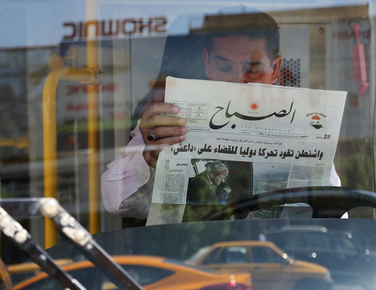 Житель Ирака читает газету о планах Барака Обамы по борьбе с Исламским государством