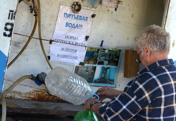 Житель Луганска набирает в канистры питьевую воду.
