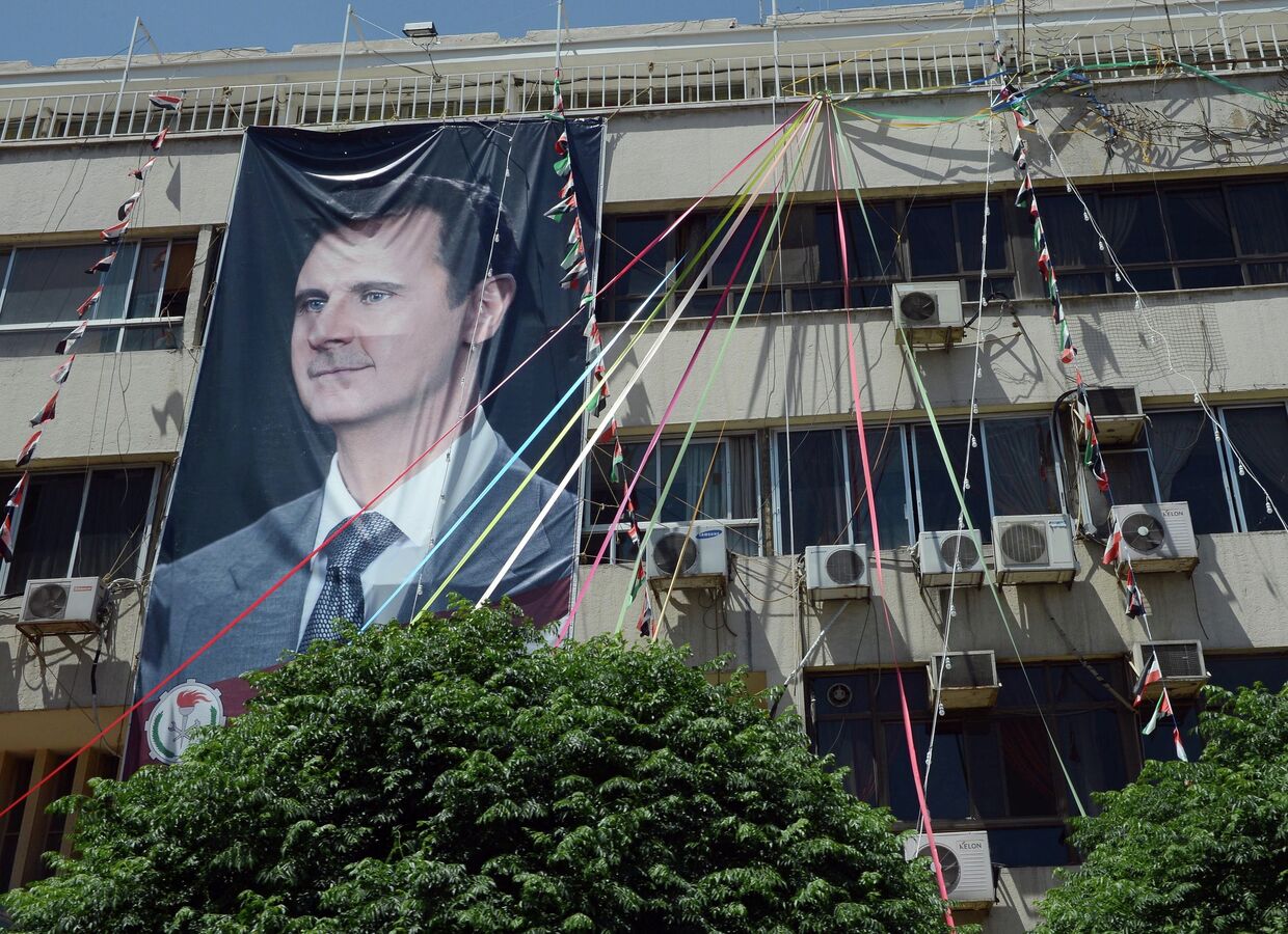 Плакат с портретом президента Сирии Башаром Асадом на здании в Дамаске