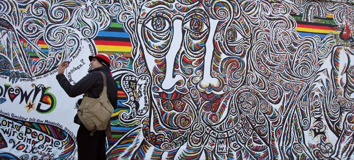 Пара фотографируется на фоне Берлинской стены