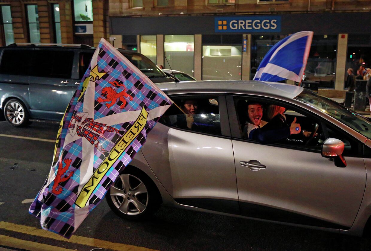Пассажир в автомобиле с флагом в центре города Глазго после закрытия избирательных участков