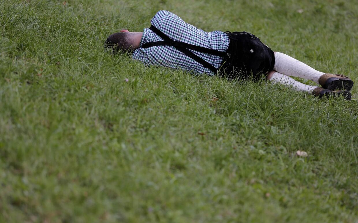 Посетитель пивного фестиваля «Октоберфест» отдыхает на лужайке