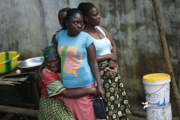 Женщина оплакивает свою дочь, умершую от лихорадки Эбола
