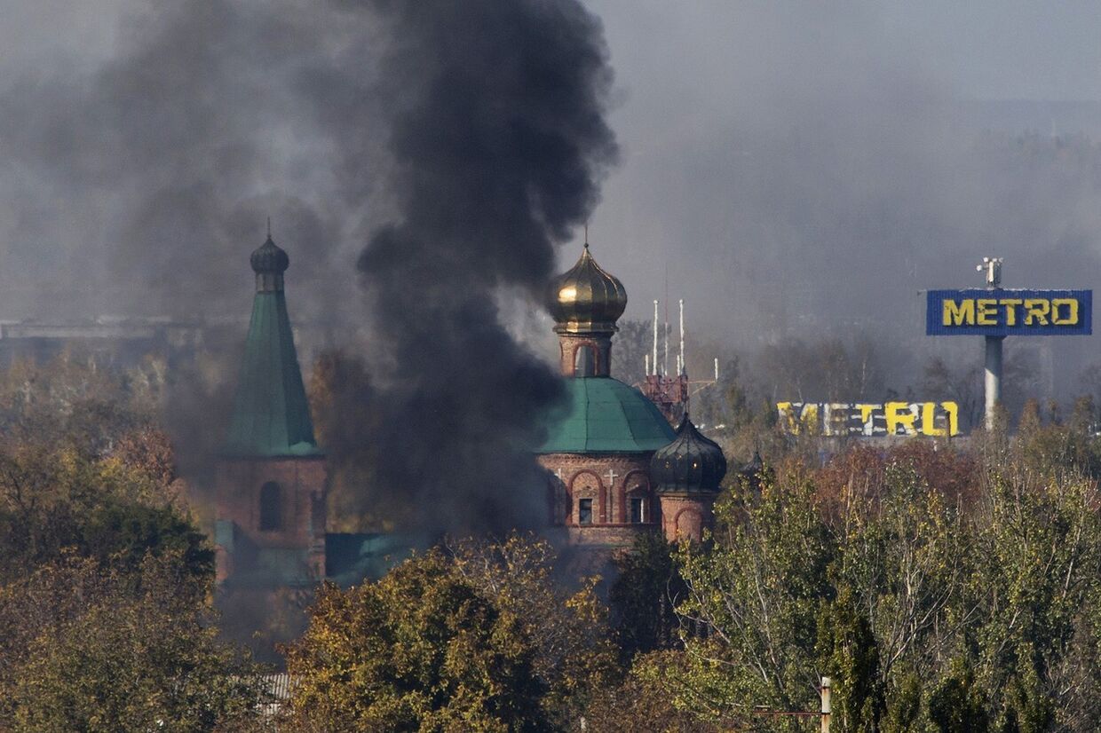 Дым поднимается над церковью во время боев в аэропорту Донецка