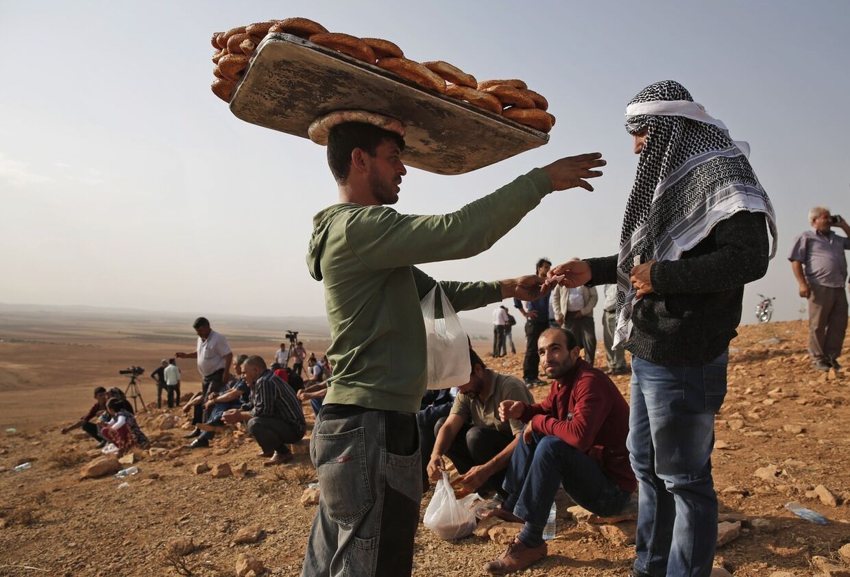 Продавец хлеба на окраине города Сурук, откуда турецкие курды смотрят на сражения в Кобани