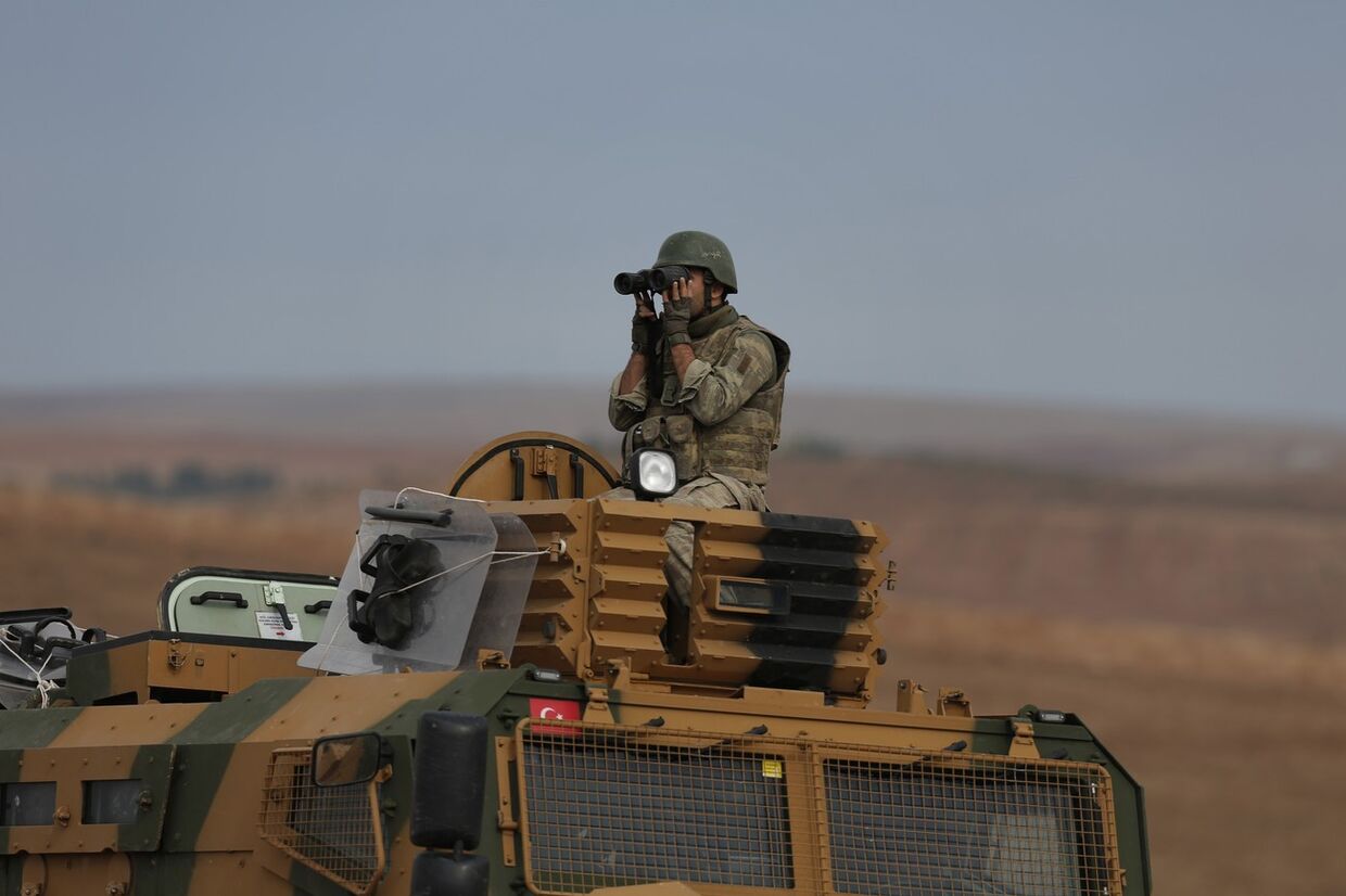 Турецкий солдат патрулирует границу с Сирией рядом с городом Кобани