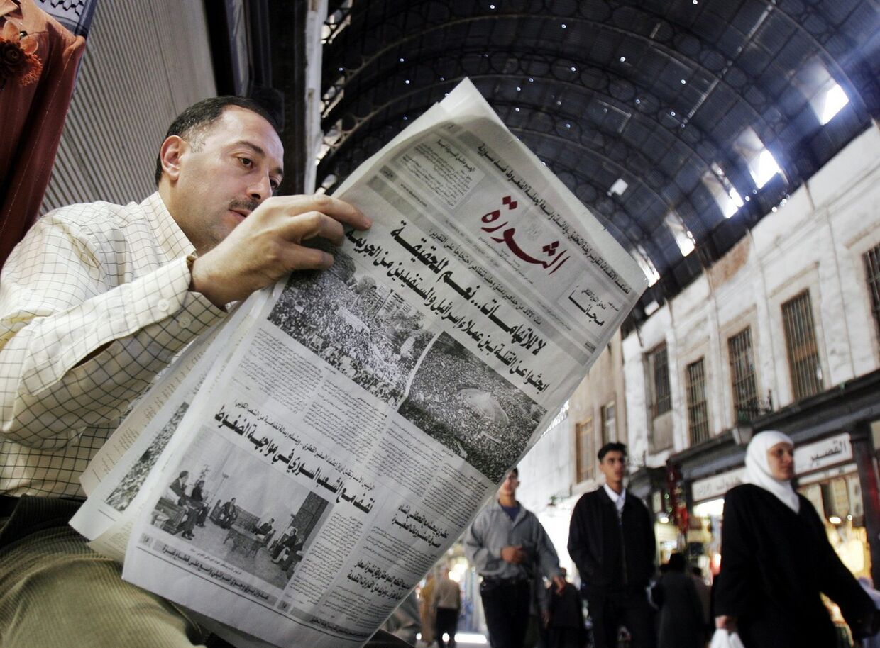Сириец читает газету на рынке в Дамаске