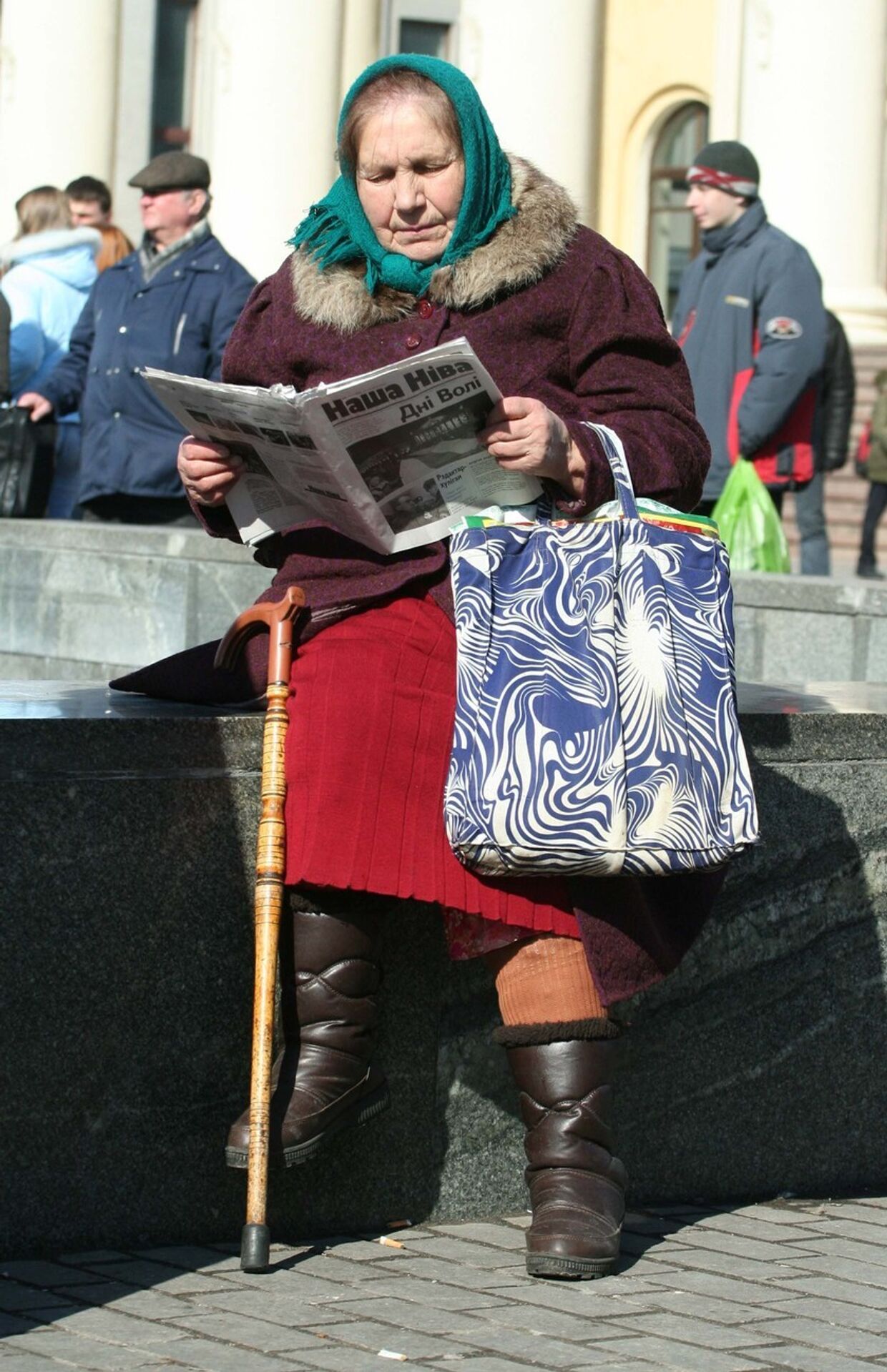 Женщина читает газету на улице Минска