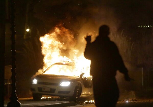 Подожженный автомобиль полиции во время беспорядков в Фергюсоне
