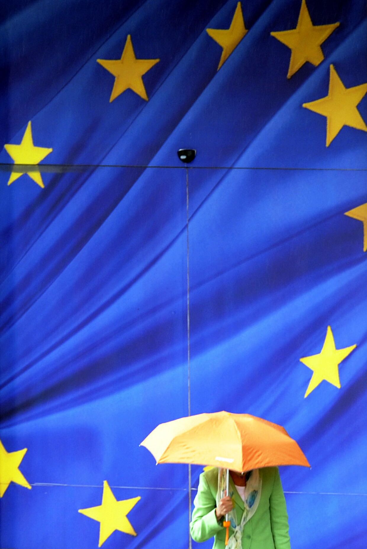 Прохожий с зонтом у символики ЕС в Брюсселе