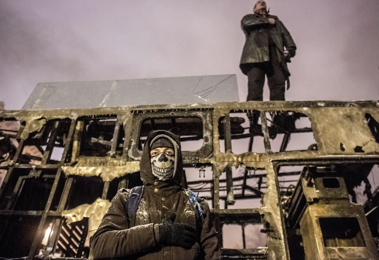 Сторонники евроинтеграции Украины на крыше выгоревшей техники на улице Грушевского в Киеве
