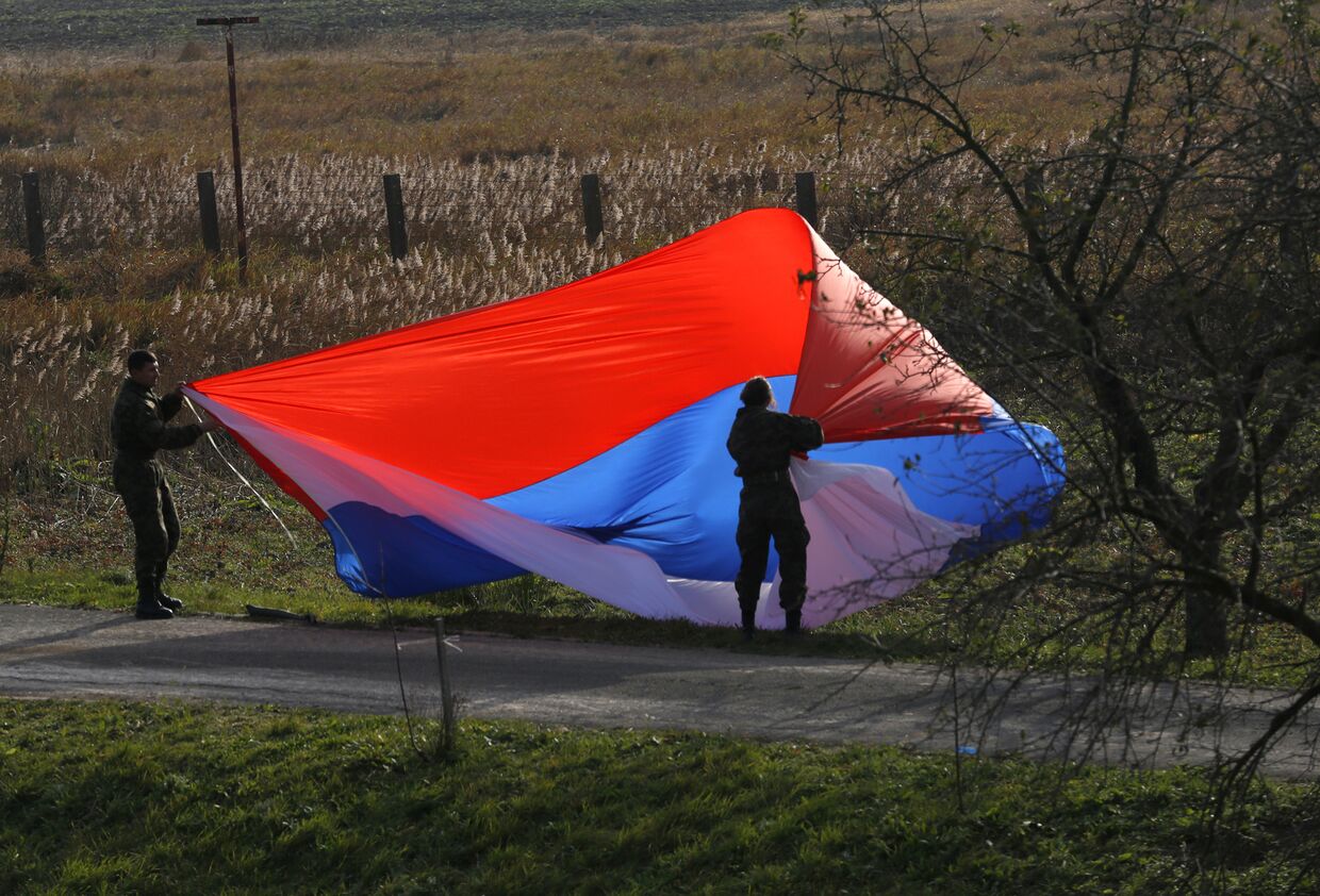 Сербские солдаты разворачивают российских флаг во время совместных с Россией антитеррористических учений