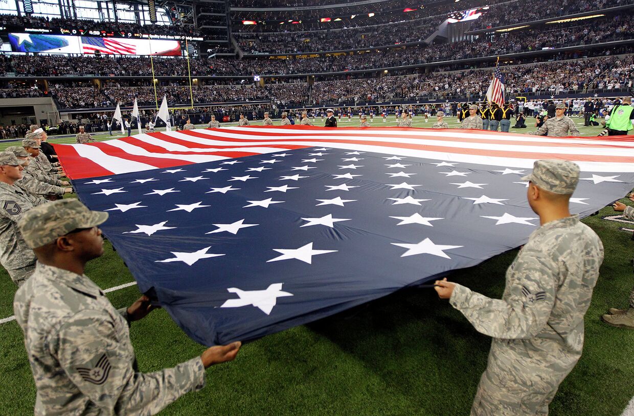 Военные США держат американский флаг перед началом игры чемпионата по американскому футболу. Техас, США
