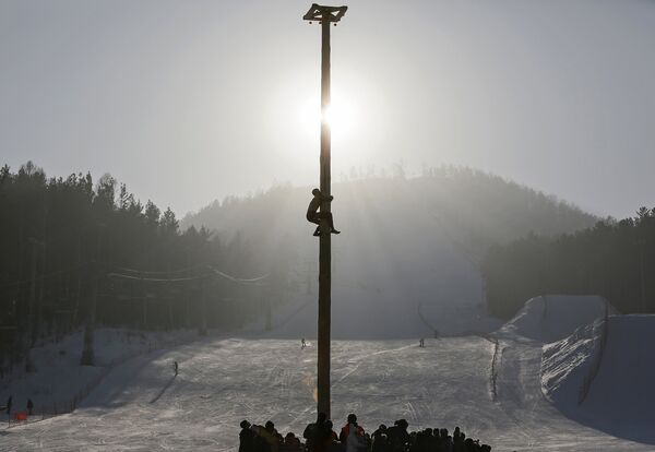 Человек залезает на 13-метровый шест во время масленичных гуляний на лыжном курорте «Бобровый лог» под Красноярском