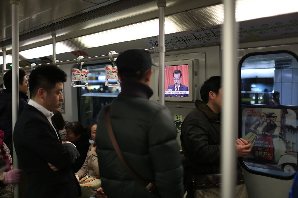 Пассажиры метро в Пекине смотрят выступление премьер-министра Ли Кэцяна на открытии ежегодной сессии Всекитайского собрания народных представителей
