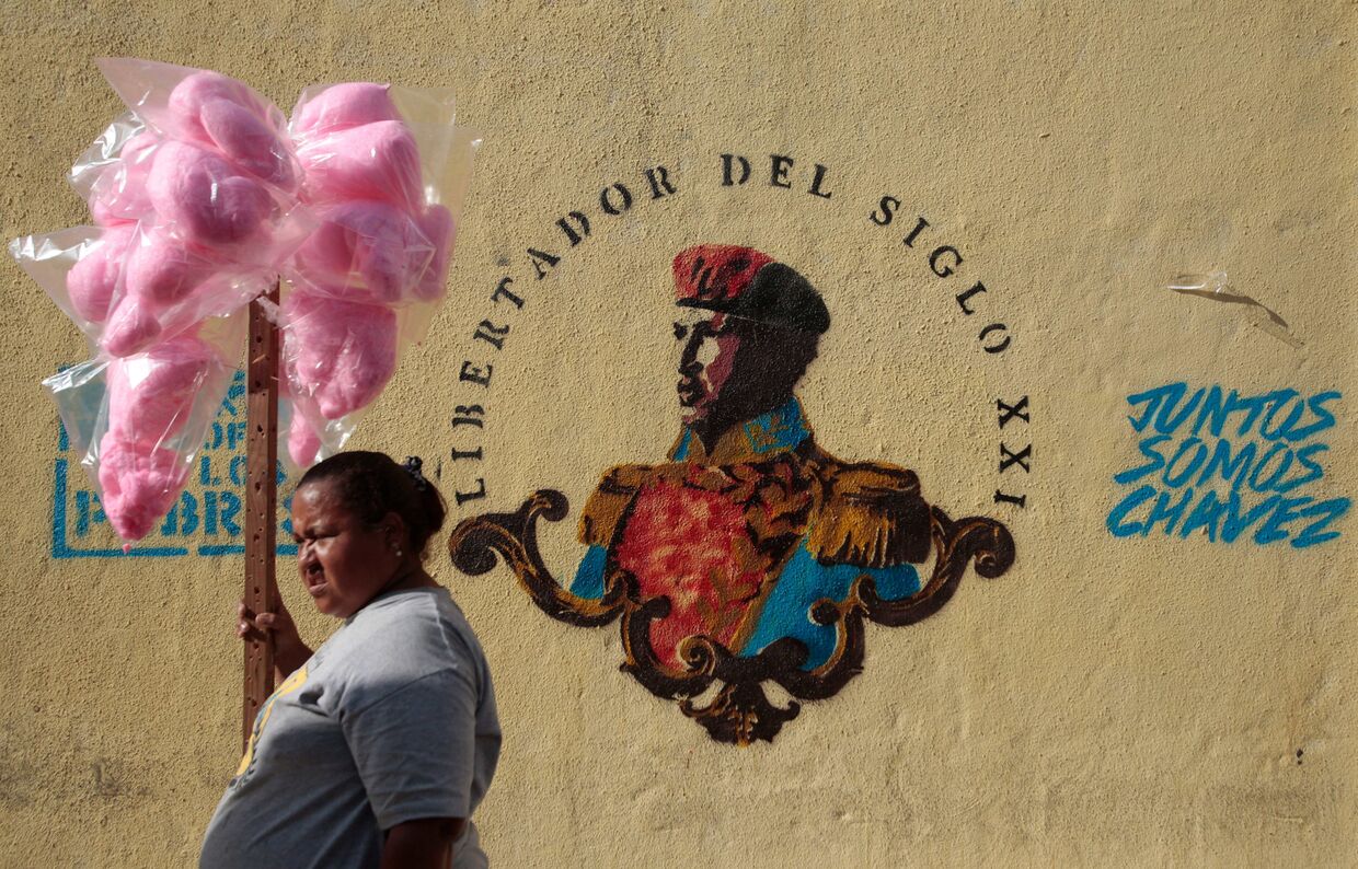 Женщина продает сахарную вату рядом с портретом Уго Чавеса