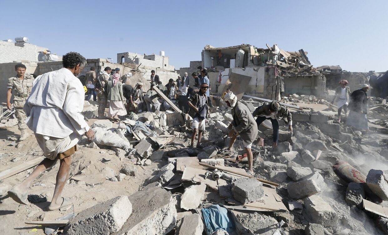 Люди разбирают обломки домов разрушенных при авиаударах вблизи аэропорта Саны