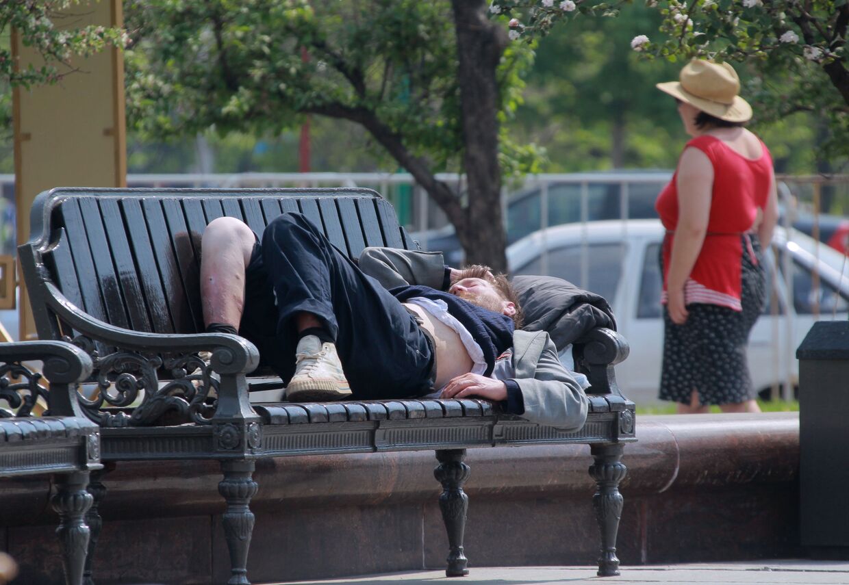 Бездомный спит на скамейке на Театральной площади