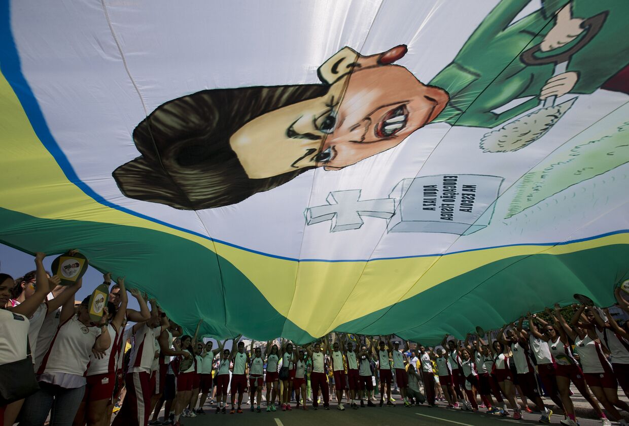Демонстранты несут баннер с карикатурой на Дилму Русеф во время акции протеста в Рио-де-Жанейро