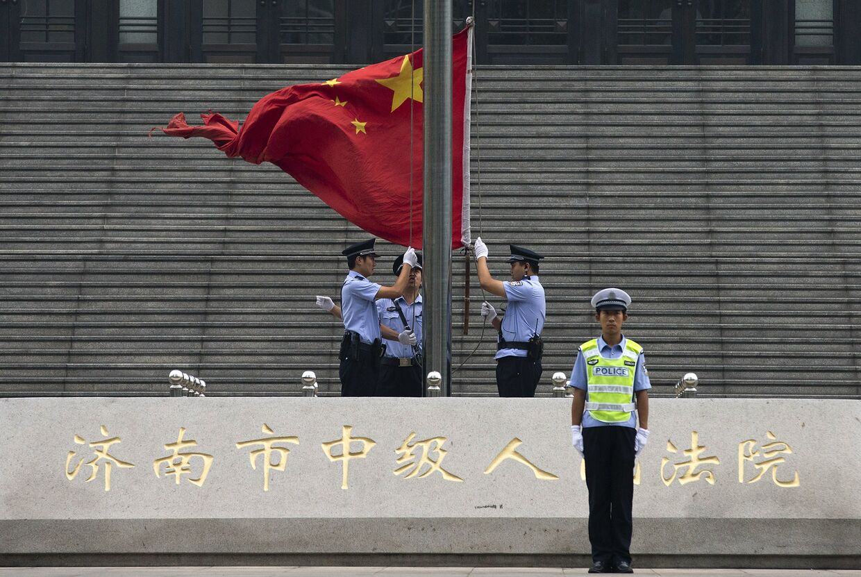 Полицейские поднимают флаг рядом со зданием суда в Цзинане, где будет разбираться дело политика Бо Силая