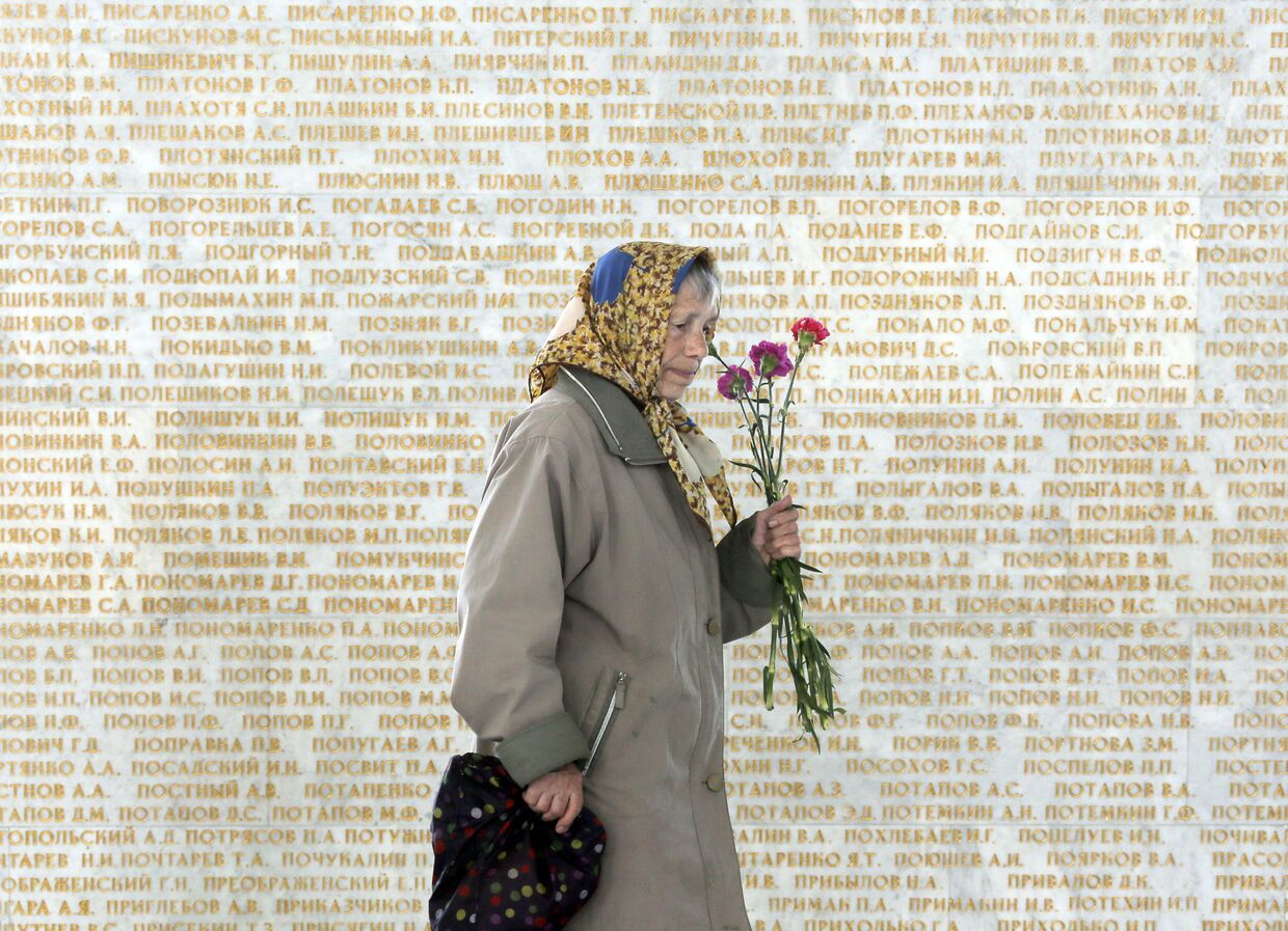 Женщина на фоне стены с именами погибших в Великой отечественной войне в Киеве